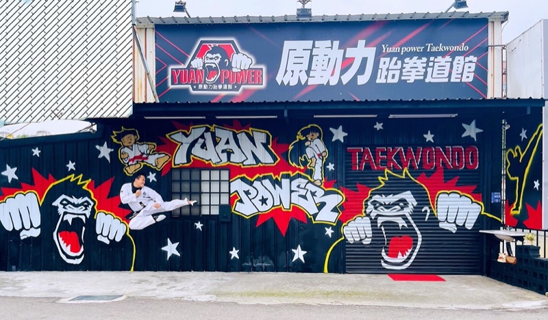 原動力跆拳道館門面,黑色外牆繪有 YUAN POWER 大猩猩塗鴉,館長袁明哲於牆前騰空側踢